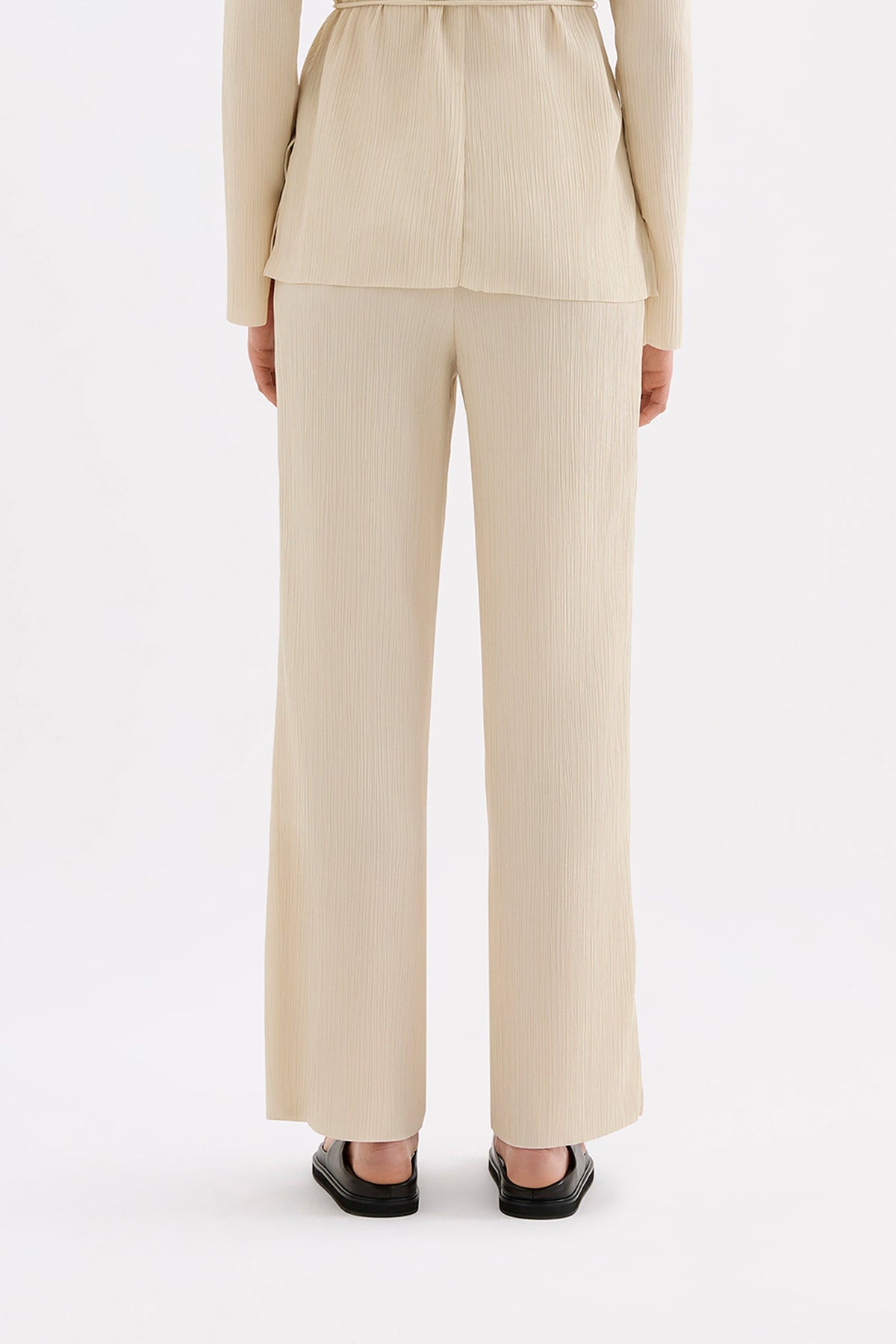 Back view of the cream full-length pants showing the relaxed straight-leg shape.