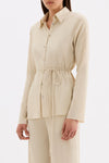 Three-quarter view of the cream fitted shirt styled with matching straight-leg pants.
