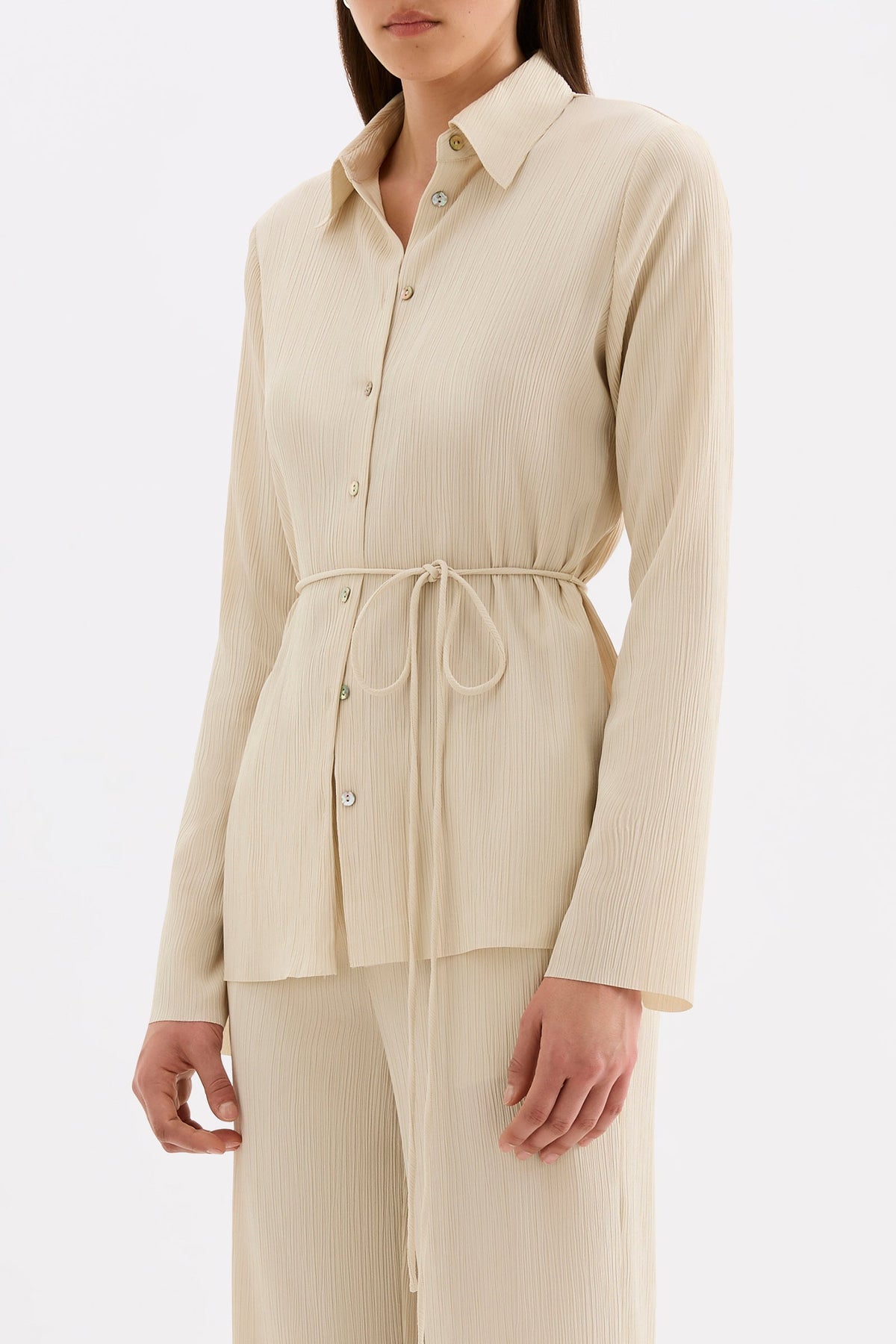 Three-quarter view of the cream fitted shirt styled with matching straight-leg pants.