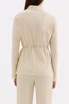 Back view showing the clean long sleeve silhouette and cinched waist of the cream shirt.