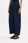 Side view of the indigo blue wide-leg pants showing the relaxed leg shape and side profile.