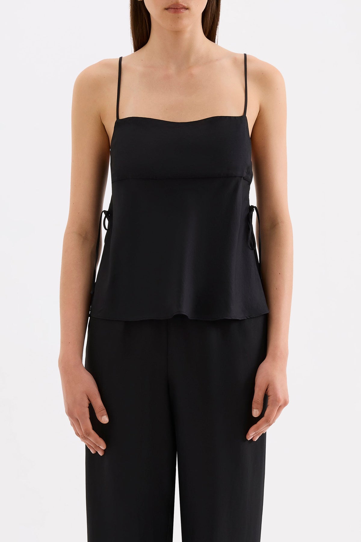Close-up front view of the black cami top showing the thin straps, straight neckline and flowing side panels.