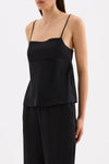 Three-quarter view of the black cami top showing the relaxed silhouette and wide side split with tie detail.
