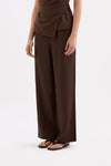 Three-quarter view showing the flowing chocolate fabric and relaxed wide-leg fit.