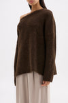 Side view of the oversized chocolate knit highlighting the soft texture and off-shoulder silhouette.