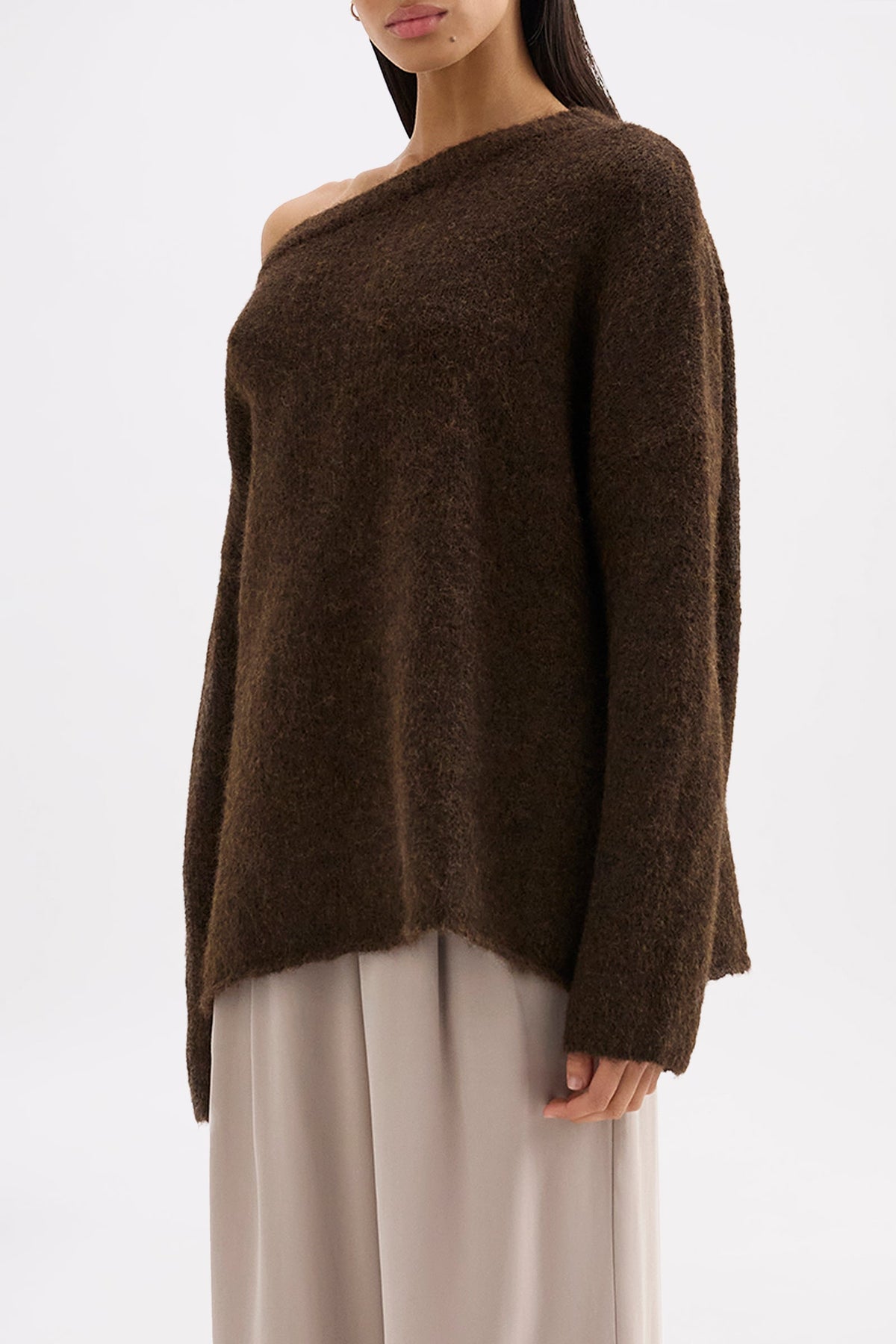 Side view of the oversized chocolate knit highlighting the soft texture and off-shoulder silhouette.
