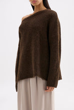 Side view of the oversized chocolate knit highlighting the soft texture and off-shoulder silhouette.