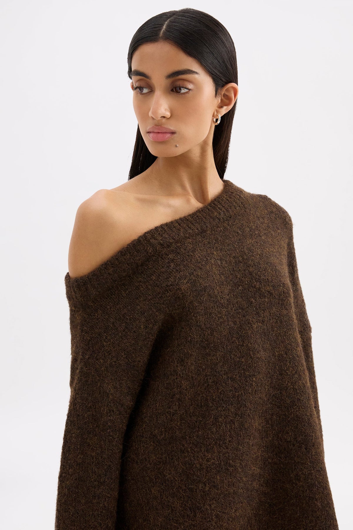 Close portrait view of the chocolate knit featuring the asymmetrical neckline and soft fluffy texture.