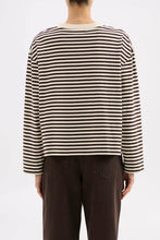 Person wearing a black and white striped shirt with brown pants on a white background
