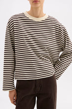 Person wearing a black and white striped sweater with a plain background