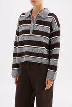 Person wearing a striped sweater with a plain background