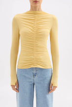 Yellow ruched long-sleeve top worn by a person on a white background
