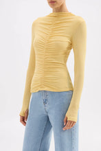 Yellow long-sleeve top worn by a person on a white background