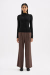Black fitted long sleeve top styled with brown wide-leg trousers in a full-length front view.
