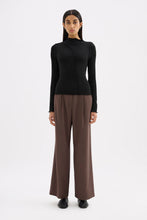 Black fitted long sleeve top styled with brown wide-leg trousers in a full-length front view.