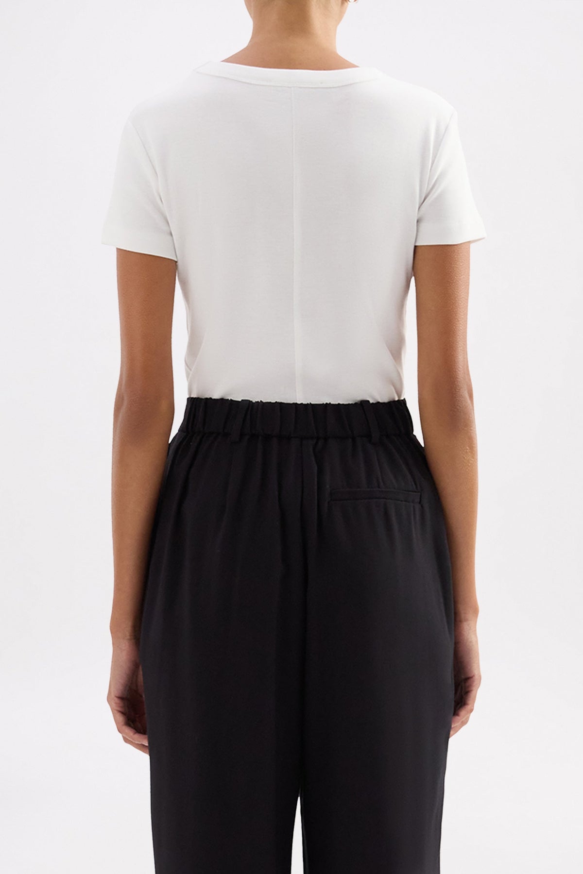 Back view showing the simple fitted silhouette and short sleeves of the white baby tee.