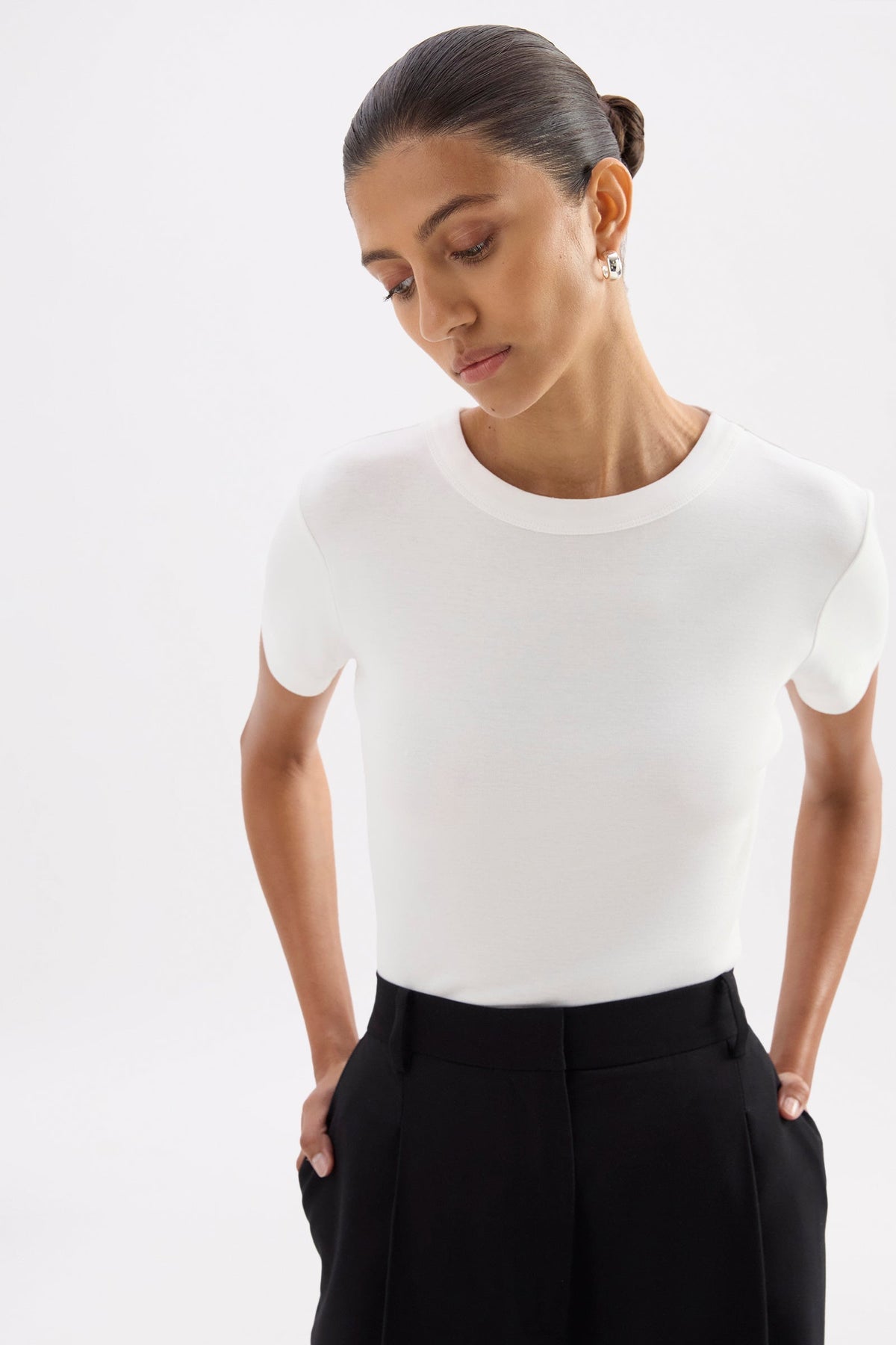 Relaxed front pose highlighting the close fit and hip-length shape of the white tee.