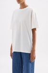Three-quarter view highlighting the oversized silhouette and dropped shoulder shape styled with blue denim.