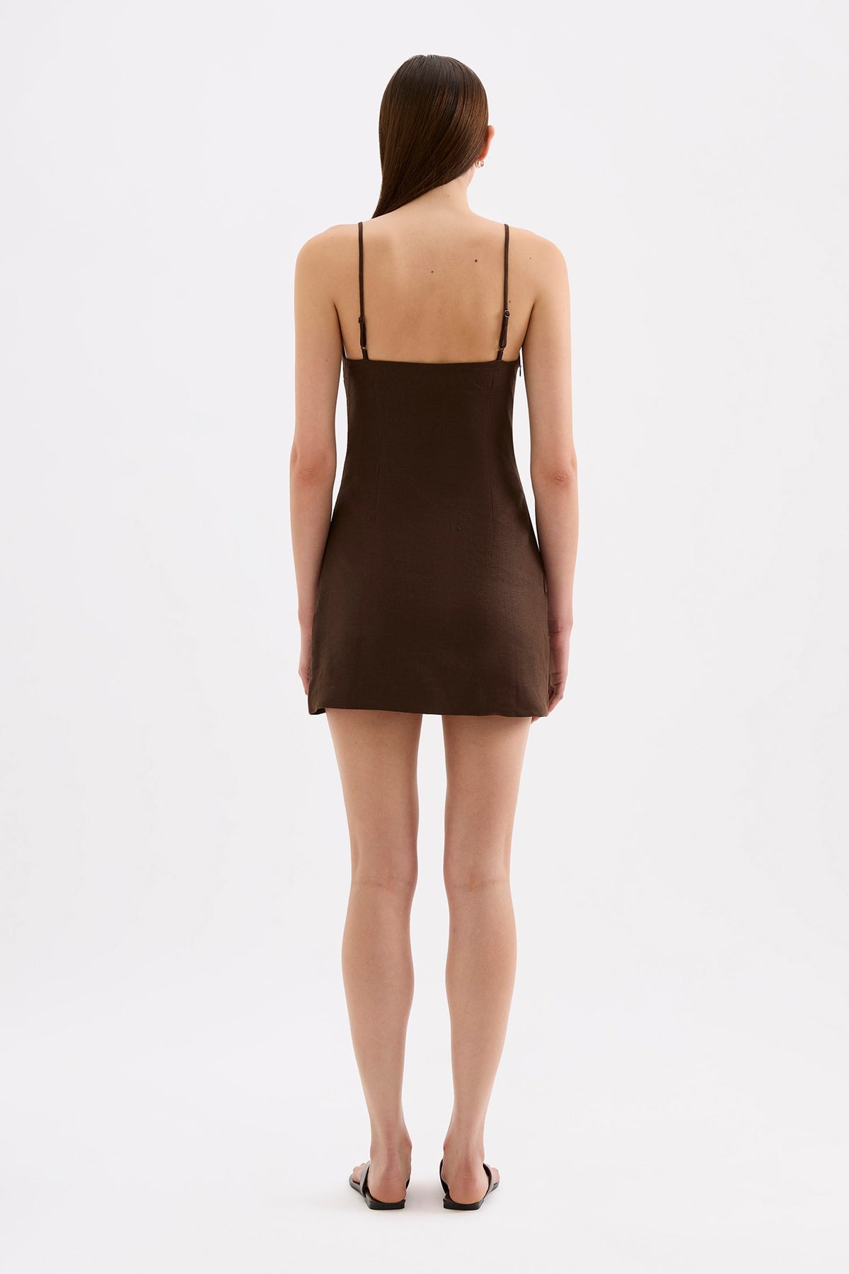 Back view of the chocolate brown mini dress showing the thin adjustable straps, fitted upper section and short skirt.