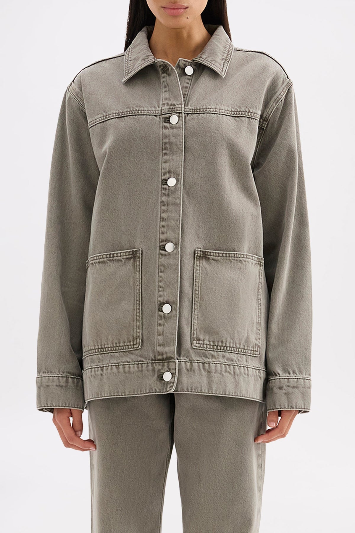 Close front view showing the collared neckline, button closure, chest seam and front patch pockets.