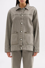 Close front view showing the collared neckline, button closure, chest seam and front patch pockets.