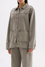 Three-quarter view highlighting the boxy silhouette, long sleeves and stone-washed denim finish.