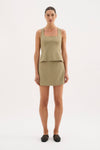 A model wears the Nude Lucy Thea Top in moss with the matching mini skirt in a full-length front view.
