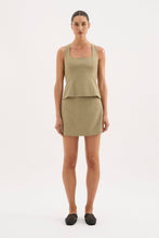 A model wears the Nude Lucy Thea Top in moss with the matching mini skirt in a full-length front view.
