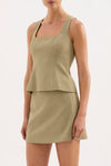 A model wears the moss Thea Top with the matching skirt in an angled front studio view.
