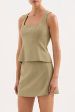 A model wears the moss Thea Top with the matching skirt in an angled front studio view.
