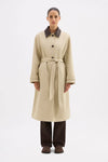 Woman wearing a beige trench coat with a belt on a white background