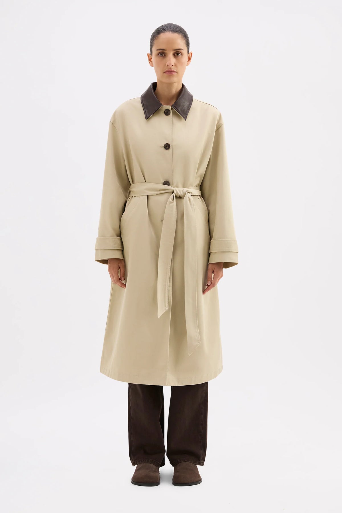 Woman wearing a beige trench coat with a belt on a white background