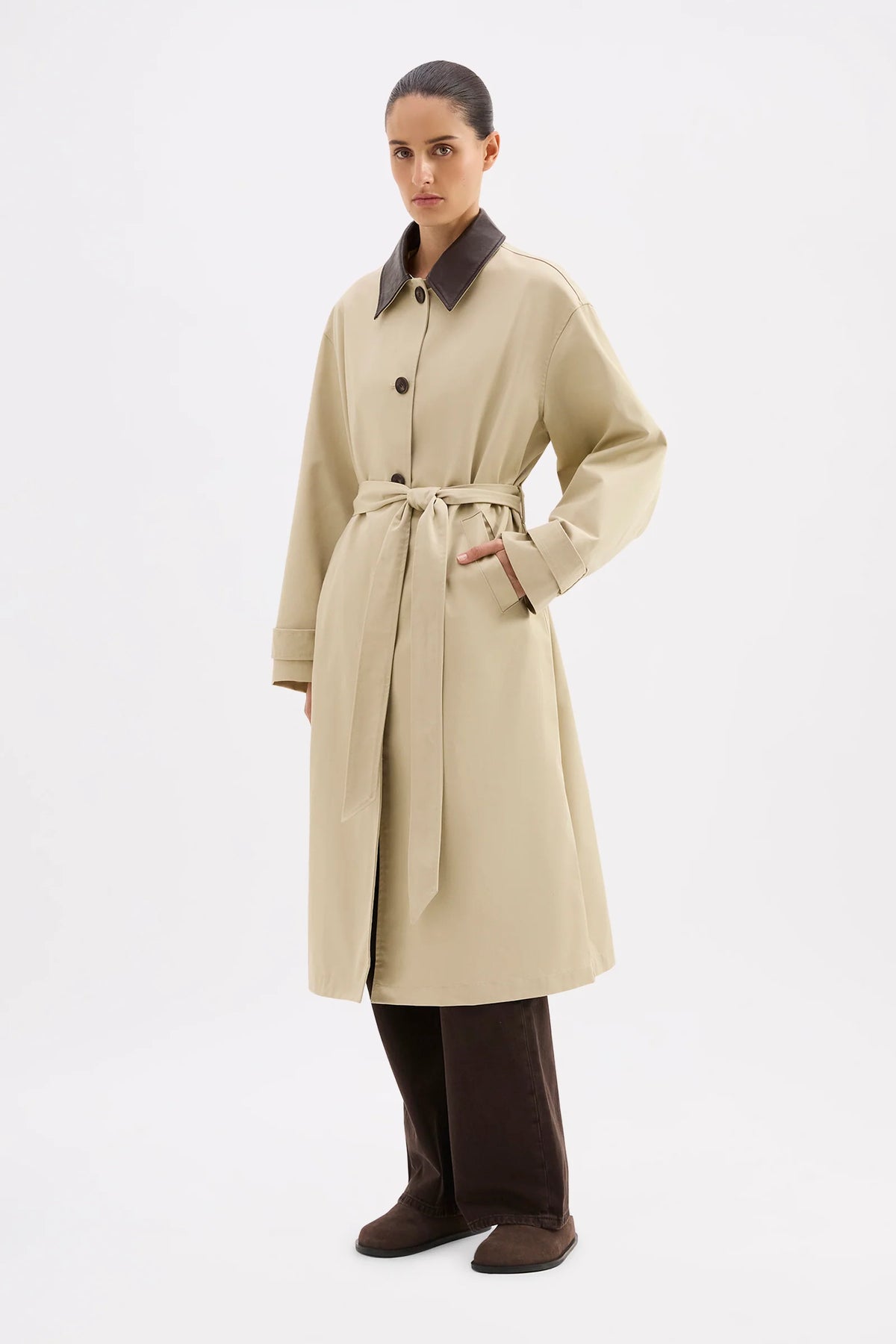 Woman wearing a beige trench coat with a brown collar on a white background