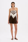 A model wears the brown and cream Vela print scarf as a strapless top with a pointed front and tied back.