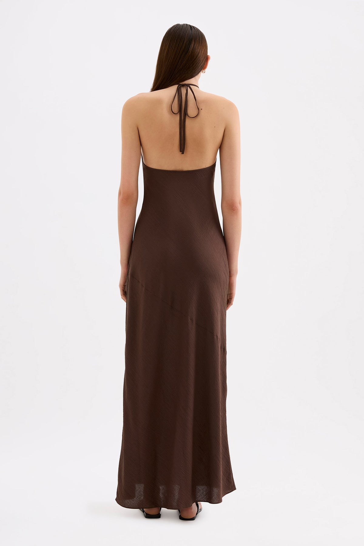 Back view of the chocolate brown maxi dress showing the halter neckline, open upper back and relaxed maxi-length skirt.