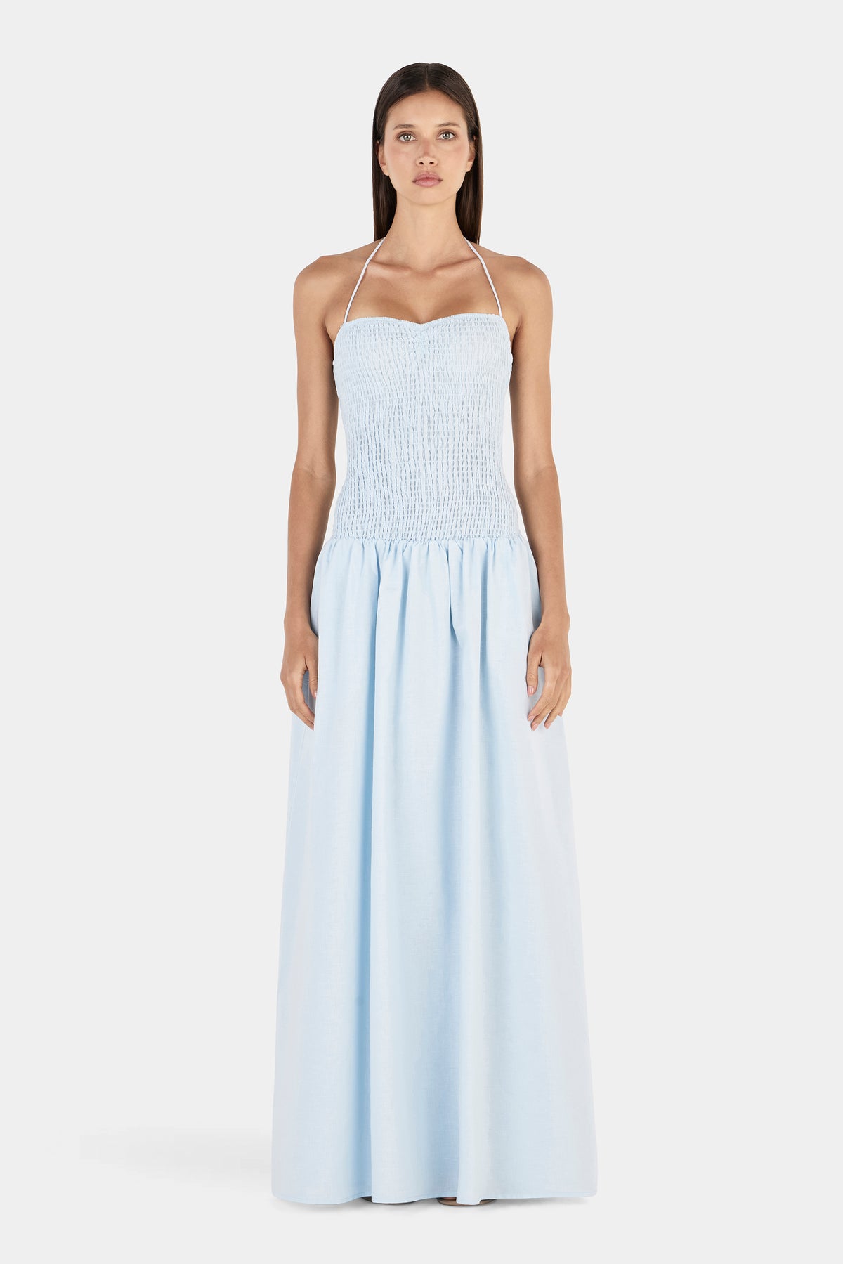 A front view of the maxi dress featuring a softly curved neckline, thin halter straps, fitted shirred bodice and gathered skirt.