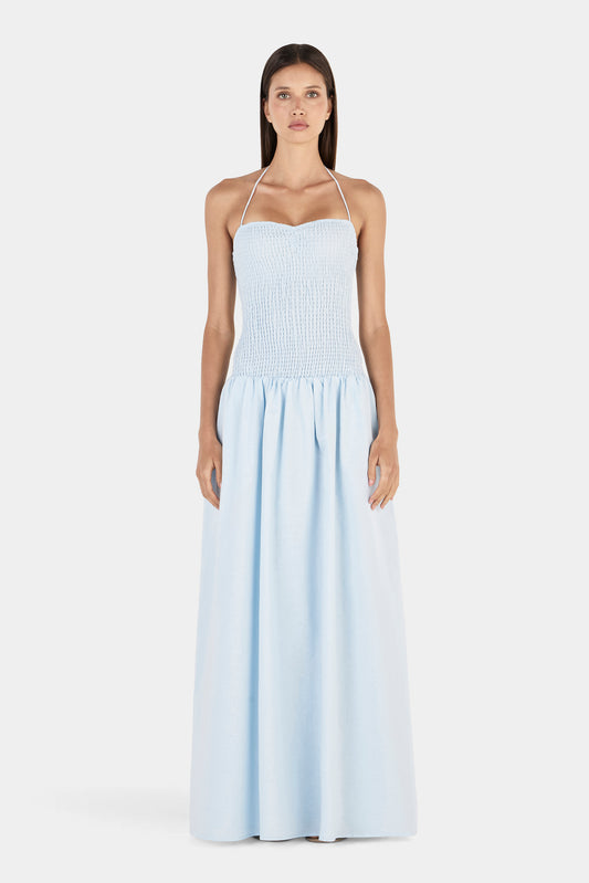 A front view of the maxi dress featuring a softly curved neckline, thin halter straps, fitted shirred bodice and gathered skirt.
