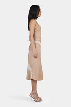 Woman wearing a beige dress with lace details on a white background