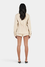 Model wearing the beige jacket with matching shorts, showing the oversized fit, waist tie and clean back silhouette, full-length back view
