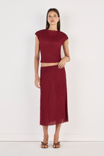 Model wearing the crimson Midi Skirt with a matching cropped top and strappy heels, showing the clean waistband, flowing midi length, lightweight crinkled texture and softly draped silhouette in a full-length front view.