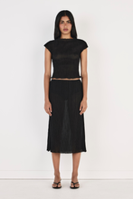 Model wearing the black top with the matching midi skirt and black heeled sandals, showing the high rounded neckline, cap sleeves, fitted cropped silhouette and softly crinkled texture in a full-length front view.