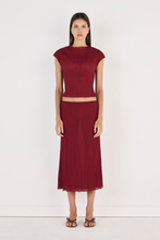 Model wearing the crimson Rita Top with the matching midi skirt and strappy heels, showing the high rounded neckline, cap sleeves, fitted cropped silhouette and softly crinkled texture in a full-length front view.