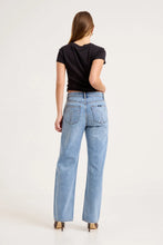 Model wearing the mid-blue boyfriend jeans with a fitted black tee and heels, showing the back yoke, signature square back pockets, relaxed seat and straight-leg silhouette in a full-length back view.