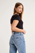 Close-up back view of the mid-blue boyfriend jeans, showing the waistband, back yoke, signature square pockets, contrast stitching and softly washed denim finish.
