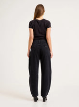 Model wearing the black barrel jeans with a fitted black tee, showing the back yoke, square rear pockets, relaxed seat and tapered ankle-length legs in a full-length back view.
