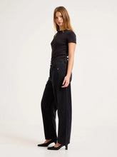 Model wearing the washed black barrel jeans with a fitted black tee and heels, showing the mid-rise waist, side seam panels, knee darts and cropped tapered hem in a full-length side view.