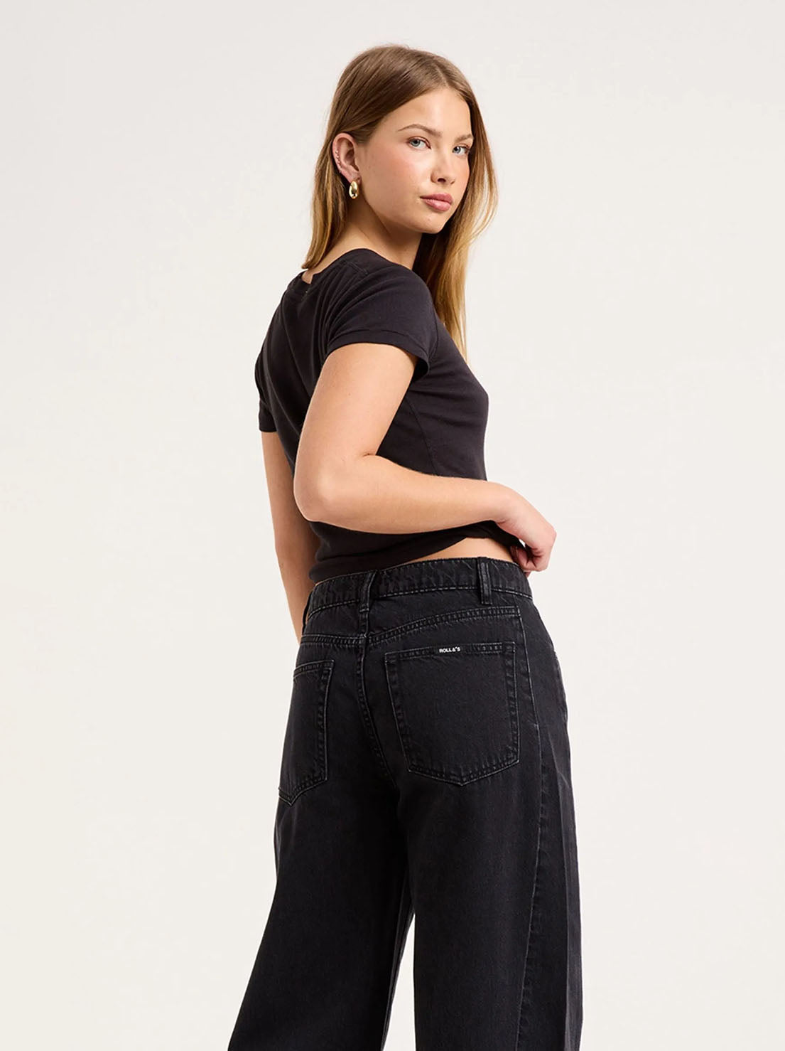 Close-up back view of the washed black jeans, showing the back yoke, square patch pockets, matching black stitching and relaxed seat.