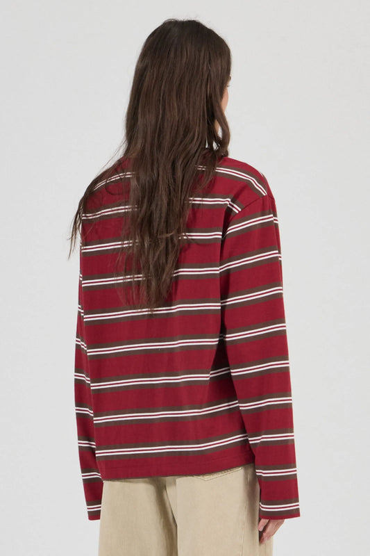 Close-up back view of the burgundy striped long-sleeve tee, showing the relaxed shoulders, horizontal stripe pattern, long sleeves and straight hem.