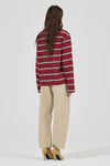 Model wearing the burgundy striped long-sleeve tee with beige jeans and tan heels, showing the dropped shoulders, straight back, long sleeves and relaxed fit in a full-length back view.