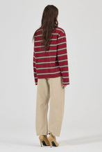 Model wearing the burgundy striped long-sleeve tee with beige jeans and tan heels, showing the dropped shoulders, straight back, long sleeves and relaxed fit in a full-length back view.